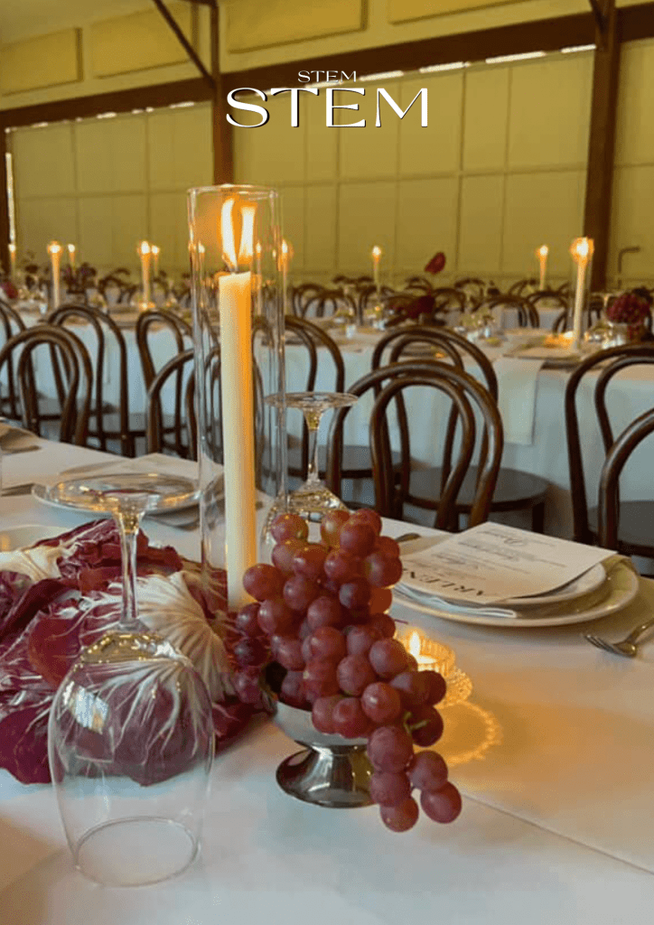 Wedding flowers at Frida’s Field Byron Bay – candlelit reception table with grapes, glassware, and organic styling by Stem Design.