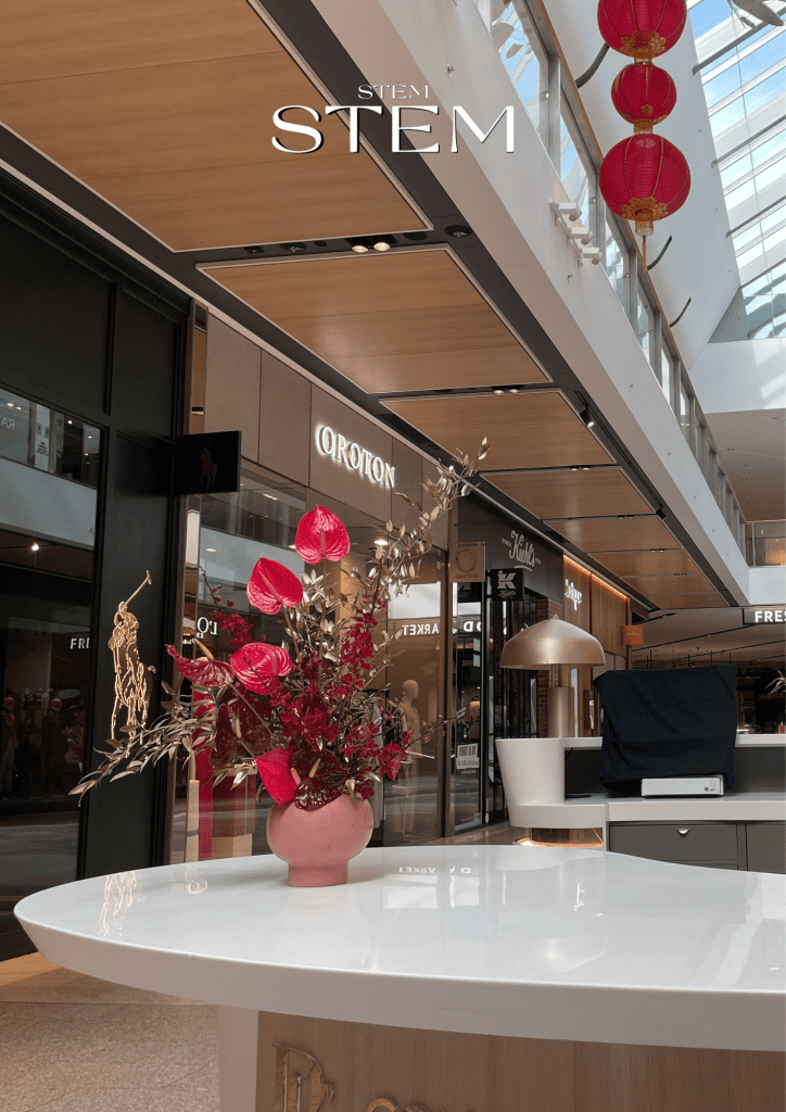 Modern office floral arrangement with red anthuriums, orchids, and gold foliage styled by Stem Design in Brisbane CBD.