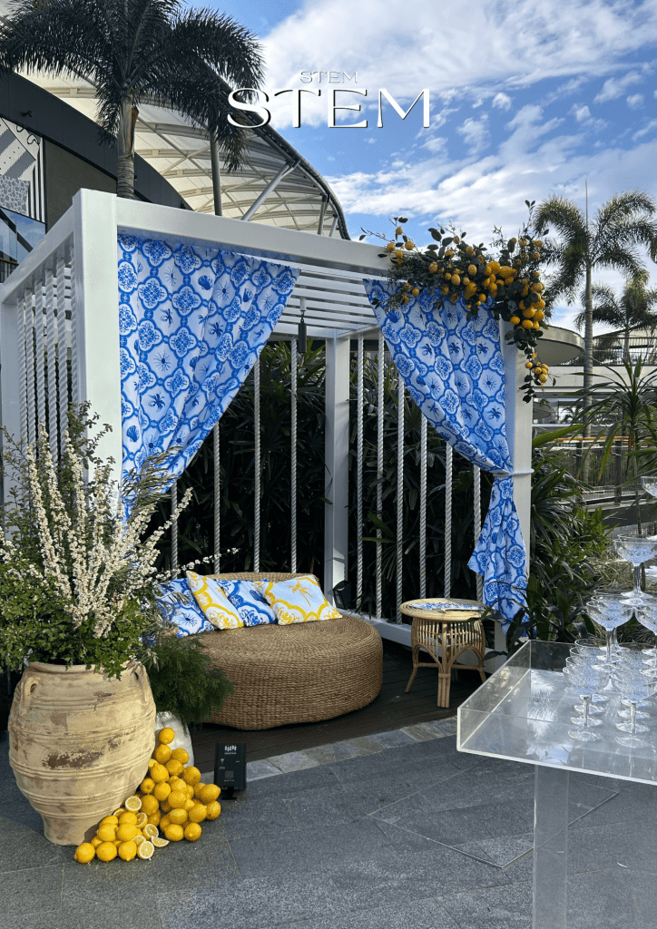 Mediterranean-inspired floral display with lemons, white florals, and blue patterned fabric styled by Stem Design for Pacific Fair’s spring summer launch.