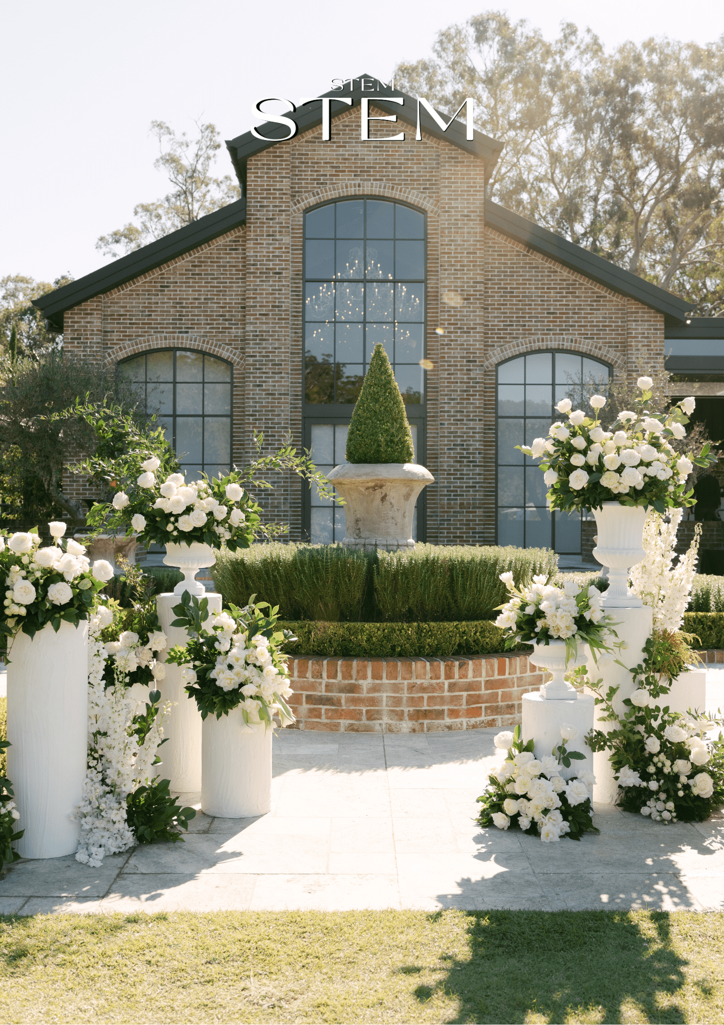 White wedding flower arrangements on pillars at an outdoor Brisbane ceremony for 2026 wedding styling.