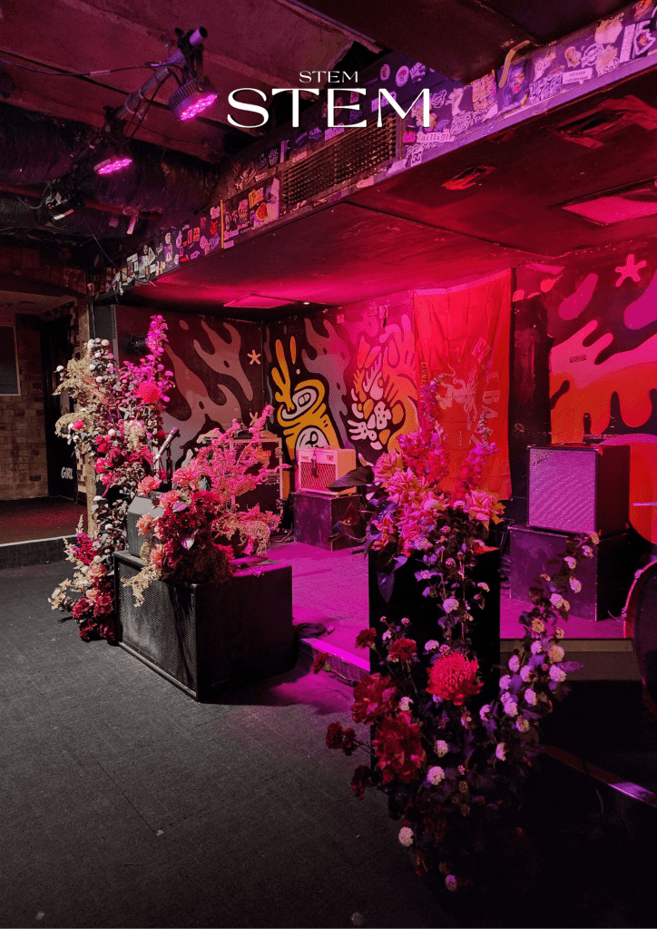 Bold red and coral wedding flower installation featuring dahlias, roses and textured greenery on the stage at Greaser in the Valley.
