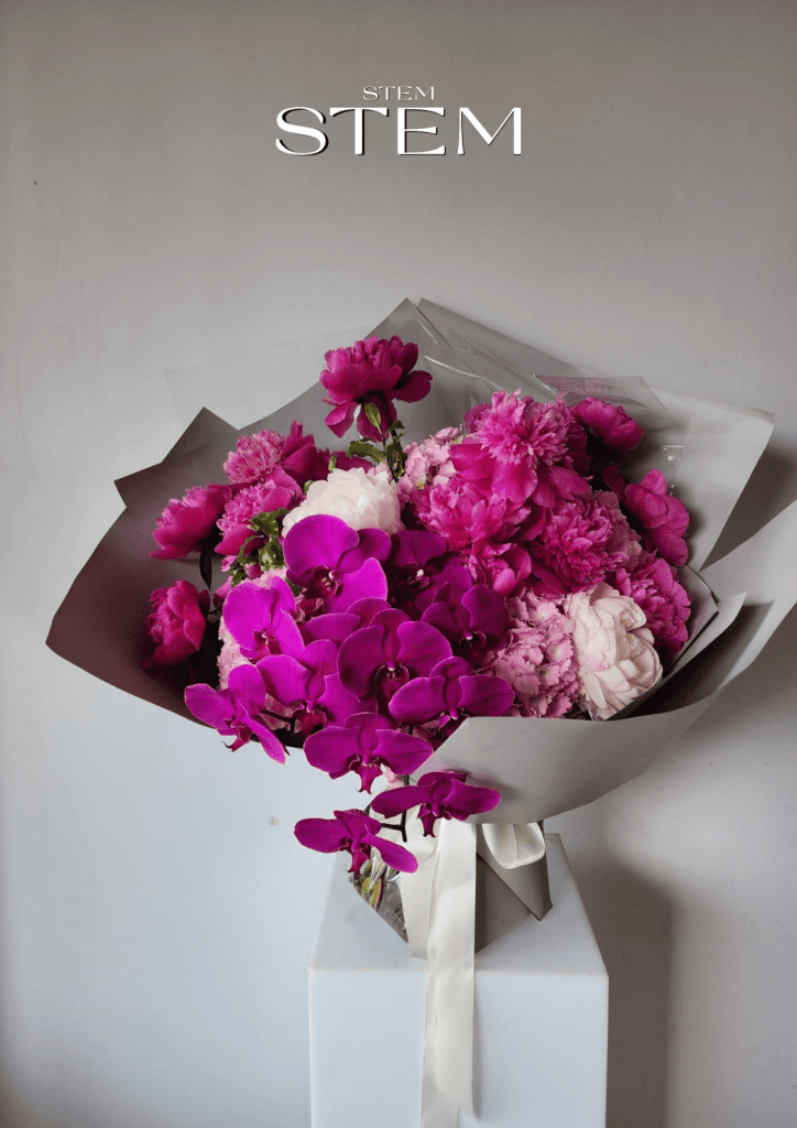 Luxury bouquet with magenta orchids, pink peonies and seasonal flowers wrapped in soft grey paper, designed by Stem Design florist Brisbane.