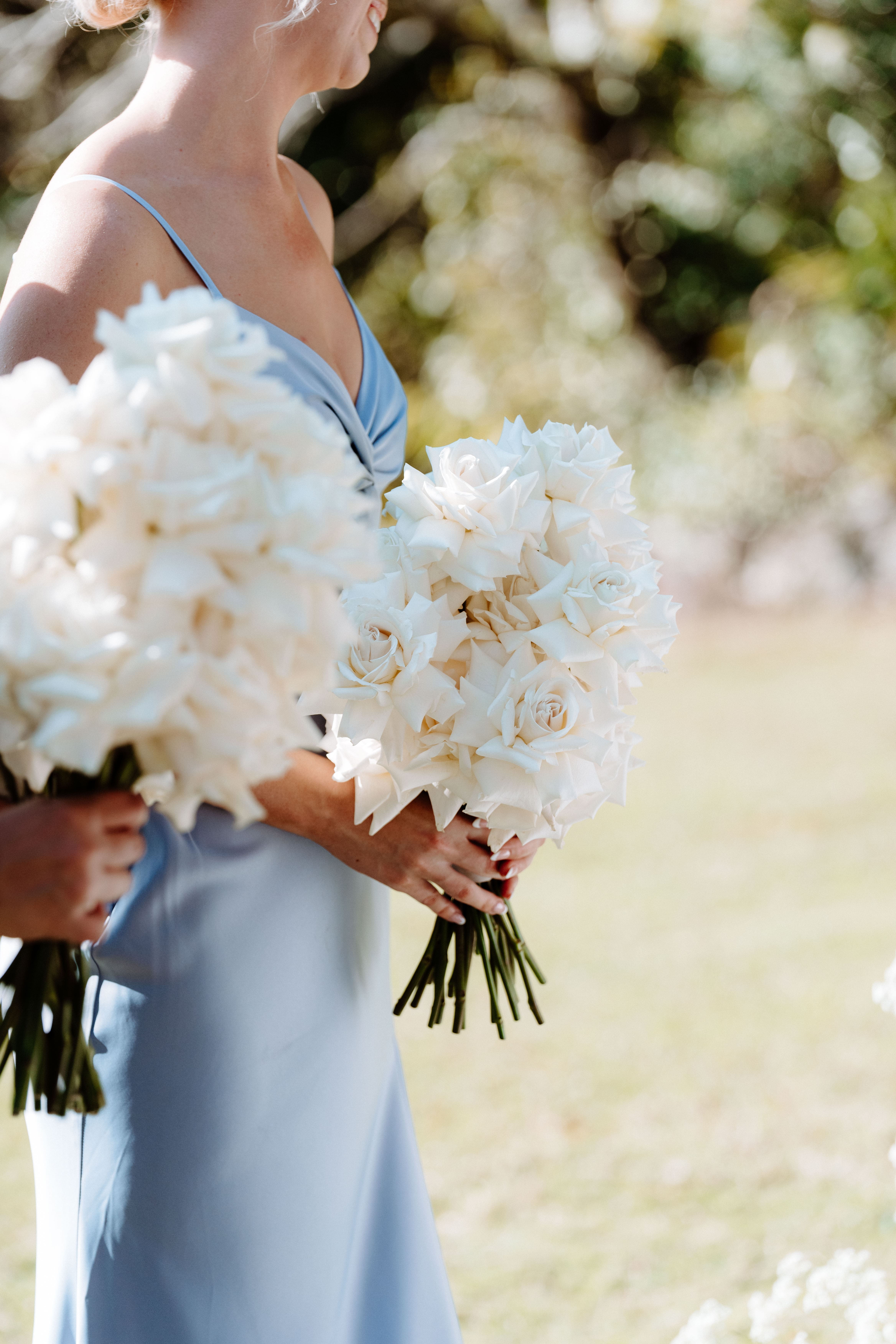 Bridesmaids holding elegant white rose bouquets designed by Stem Design for a luxury Brisbane wedding ceremony.